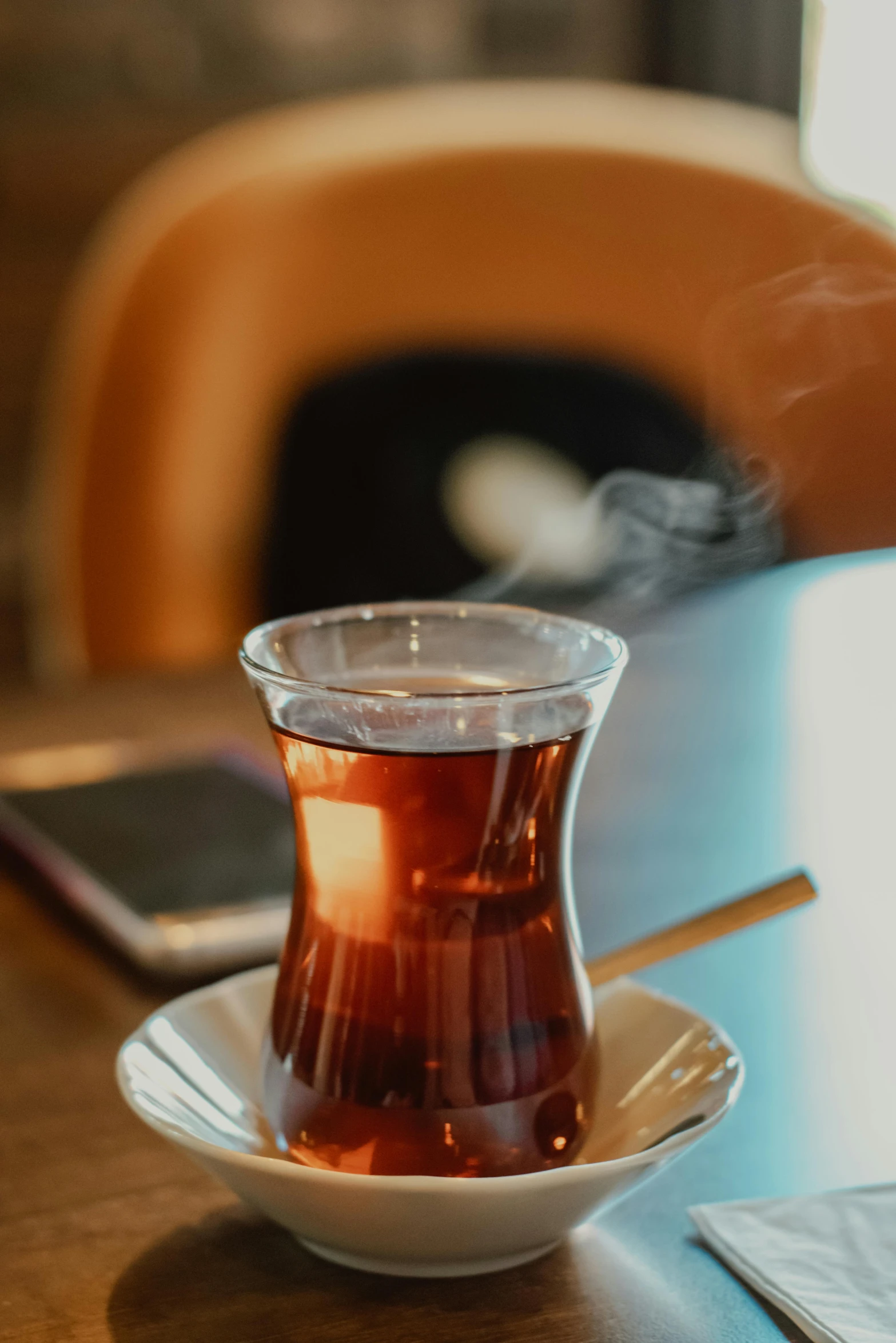 a cup of tea on a saucer on a table, by irakli nadar, hurufiyya, sitting in a cafe, whiskey, photograph taken in 2 0 2 0, family friendly