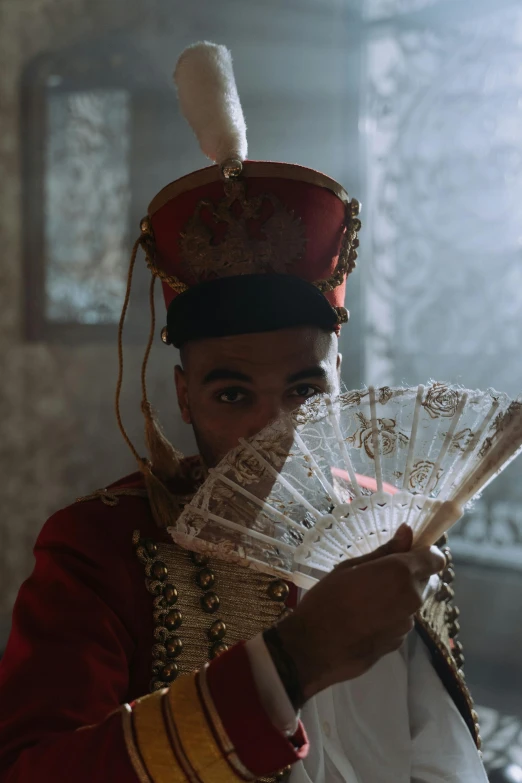 a man in a royal costume holds up a fan