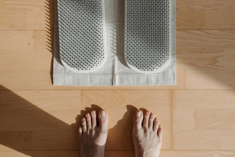 a person standing on top of a wooden floor, inspired by Victorine Foot, minimalism, foot wraps, silver，ivory, spa, soft pads