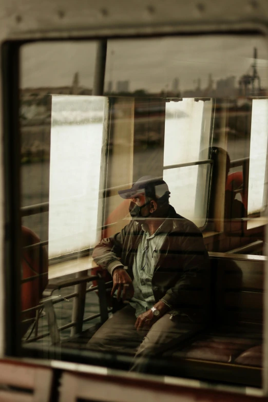 a man sitting on a train looking out the window, by Joze Ciuha, wearing facemask and sunglasses, photo taken from a boat, slide show, grain”