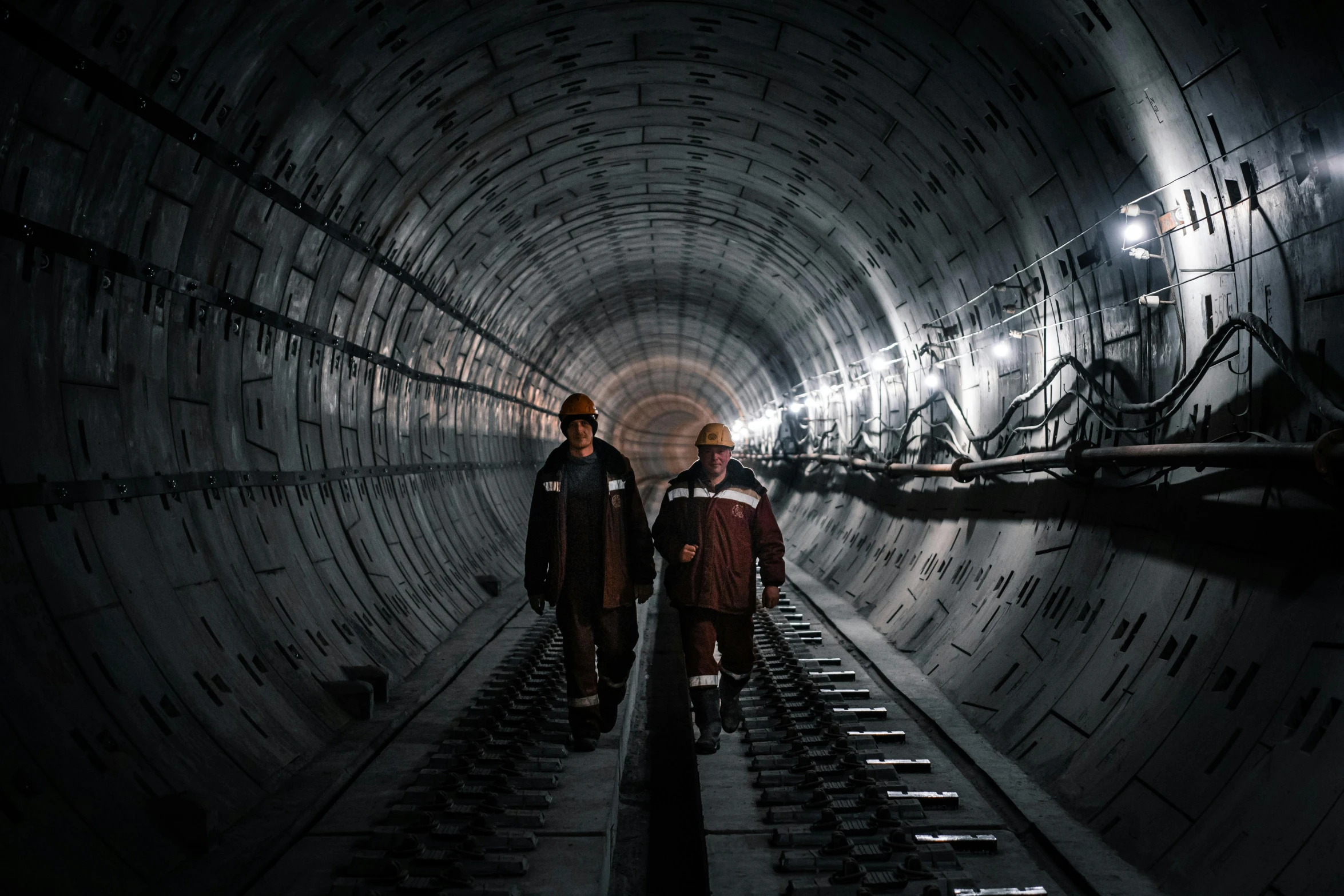 two people standing in the middle of a dark tunnel