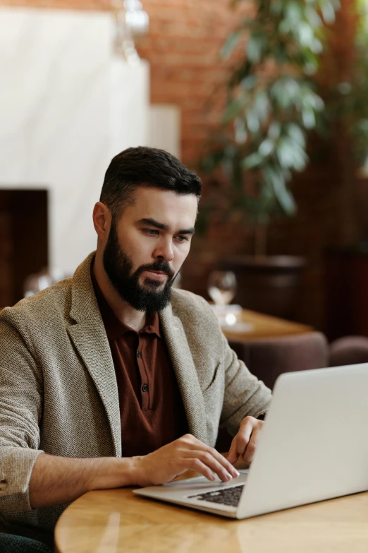 a man sitting at a table with a laptop, trending on pexels, renaissance, professional profile picture, bearded, brown, non-binary