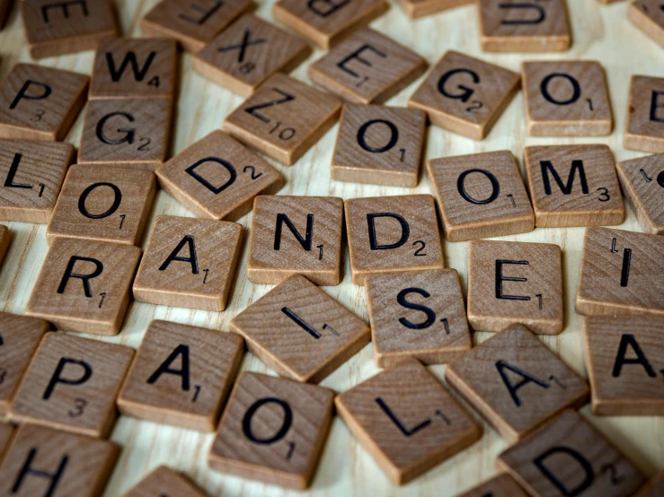 a pile of scrabbles sitting on top of a table, by Emma Andijewska, pexels contest winner, letterism, brown, random english words, background image, micro expressions