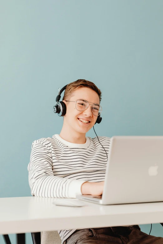 a man sitting at a table with a laptop and headphones, by Julia Pishtar, trending on pexels, earing a shirt laughing, floating headsets, non-binary, discord profile picture