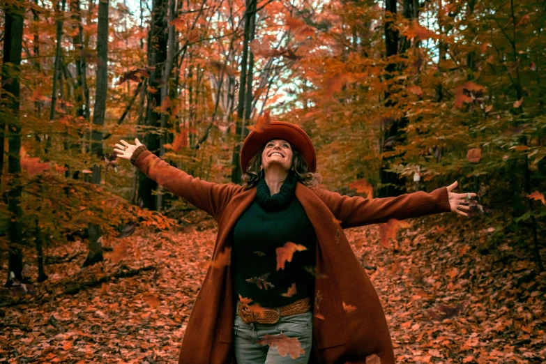 a woman standing in the middle of a forest, pexels contest winner, harvest fall vibrance, she expressing joy, brown clothes, avatar image