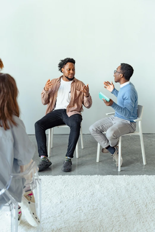 a group of people sitting on chairs in a room, talking, black man, two men, mental health