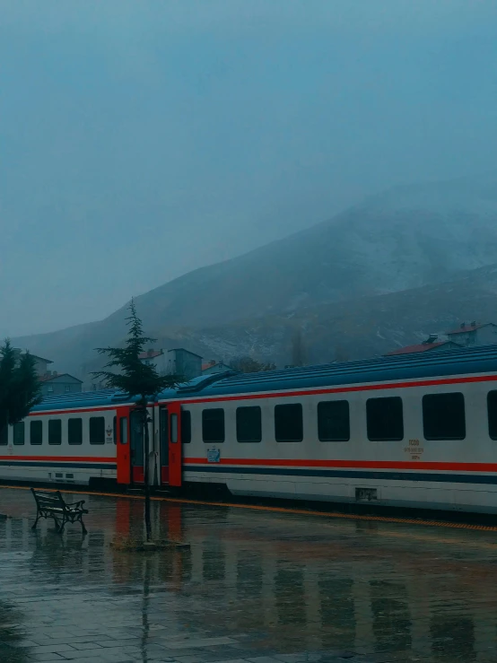 a passenger train passing through some rain soaked countryside