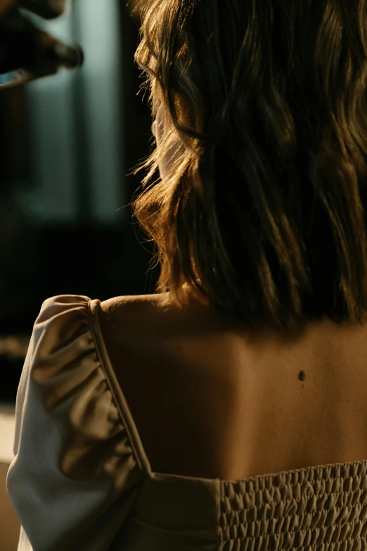 a woman sitting at a table with a wine glass in her hand, a tattoo, inspired by Nan Goldin, trending on pexels, open back dress, evening lighting, 4 k film still, girl with brown hair