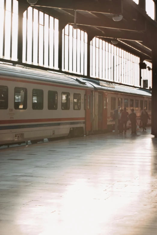 a train that is sitting in a train station, late afternoon, taken on a 1990s camera, full of people, :: morning