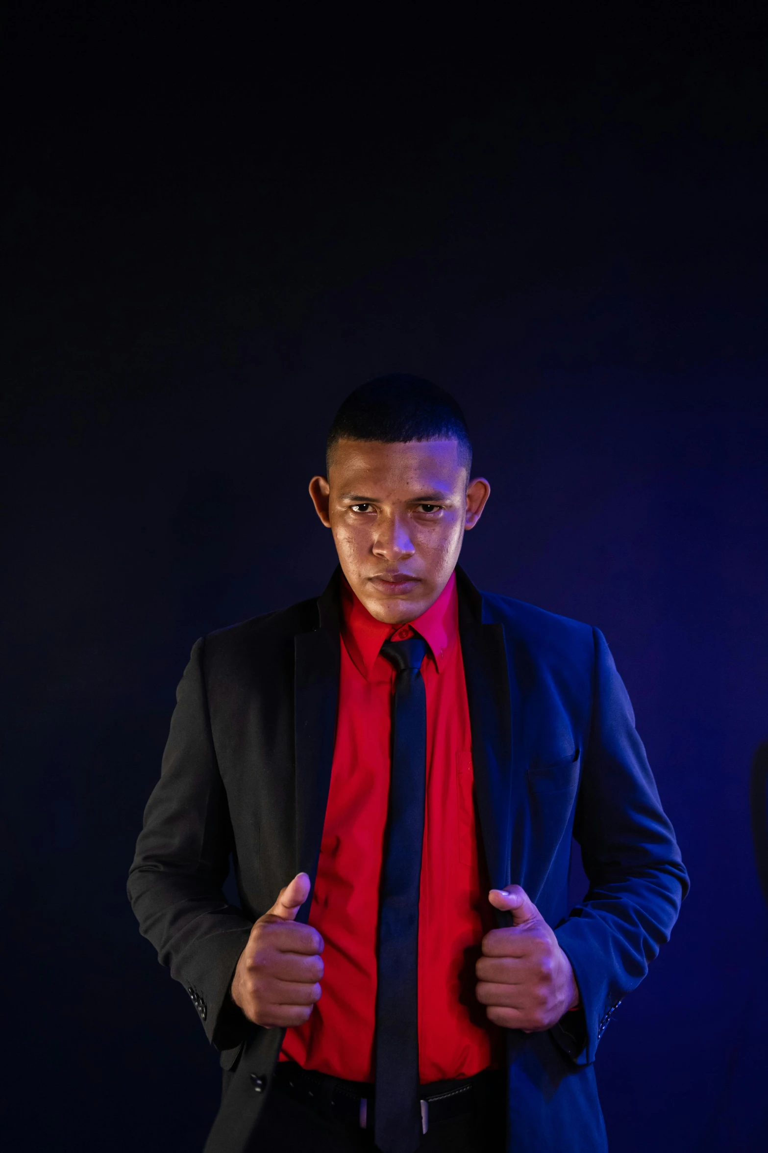 a man in a black suit and red shirt, an album cover, inspired by Randy Vargas, pexels contest winner, posing ready for a fight, lookalike, security agent, bisexual lighting