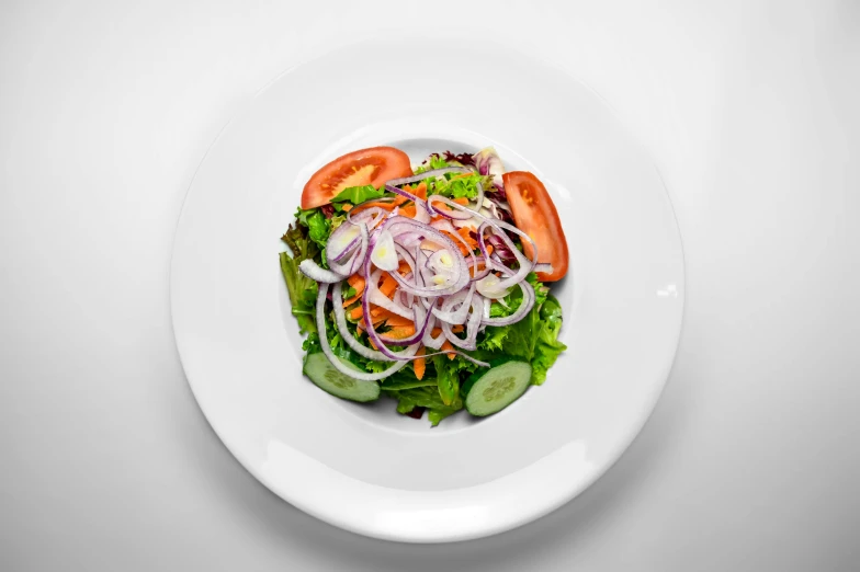 a white plate topped with a salad on top of a table, product image