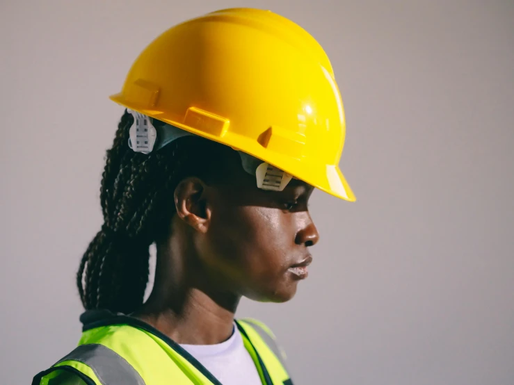 a woman wearing a hard hat and safety vest, a portrait, inspired by Afewerk Tekle, trending on pexels, close - up profile, lachlan bailey, black female, reconstruction