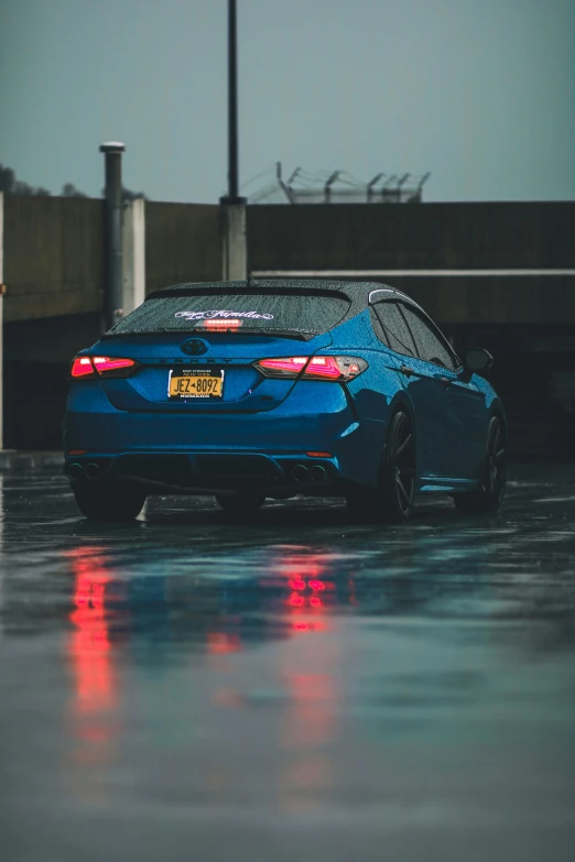 a blue sports car in the rain, with water on its rim