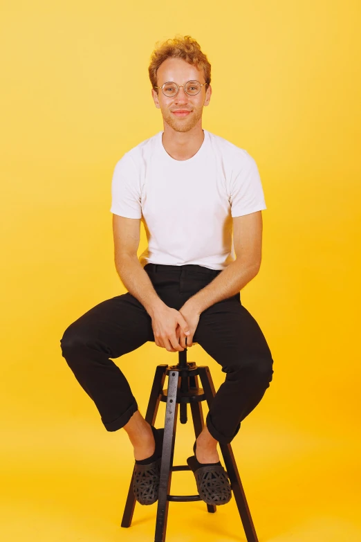 the young man is posing for a picture on the stool