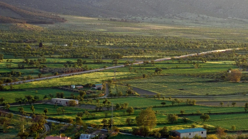 an aerial s of green fields and mountain side