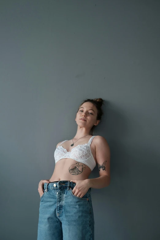 a person standing up in jeans near a wall