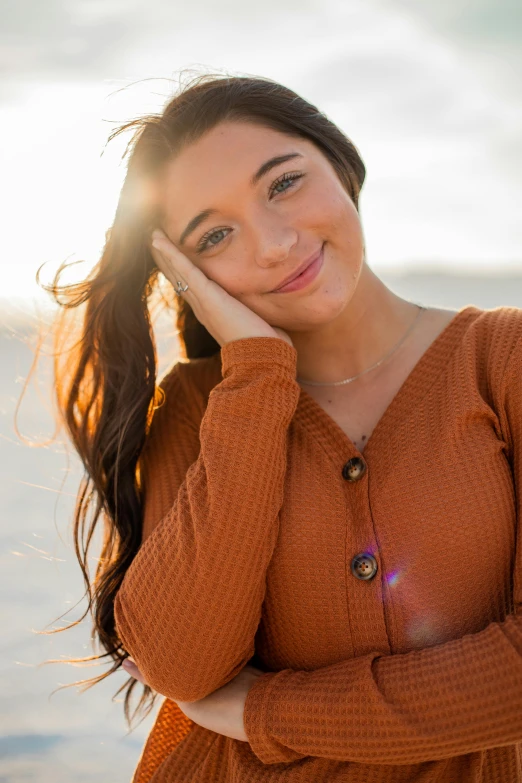 a woman standing in front of a body of water, a portrait, trending on pexels, dslr photo of a pretty teen girl, orange hue, smiling down from above, on beach