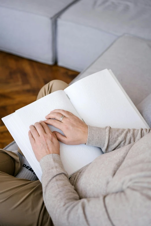 a man sitting on a couch reading a book, a drawing, by Dan Content, trending on unsplash, blank paper, sitting with wrists together, soft white rubber, diary on her hand