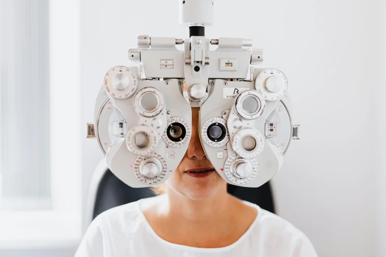 a woman with a pair of glasses on her head, trending on unsplash, medical machinery, giant eyeballs, a very macular woman in white, medical photography