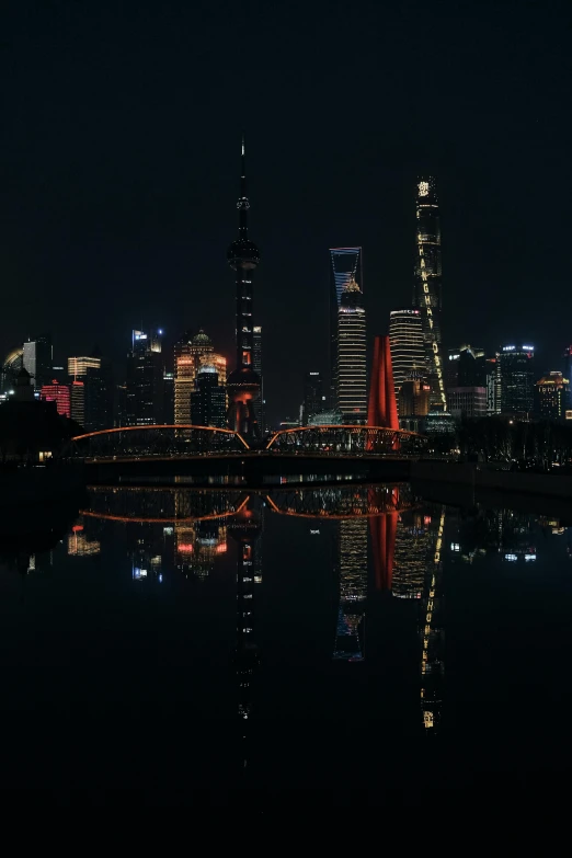 the city skyline at night is reflected in the water