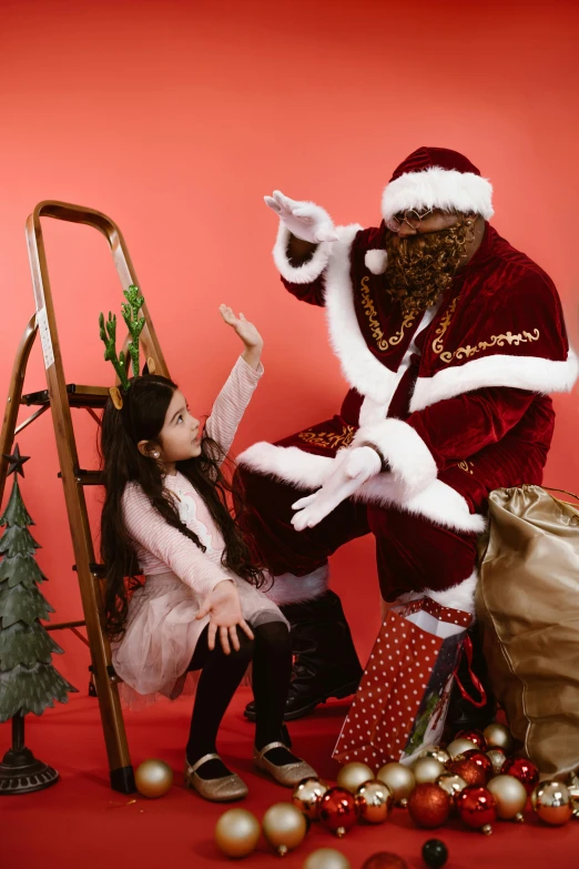 little girl sitting near santa clause and a ladder