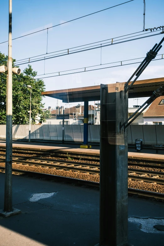 a train traveling down train tracks next to a train station, a picture, by Niko Henrichon, 2022 photograph, square lines, view from back, bus stop