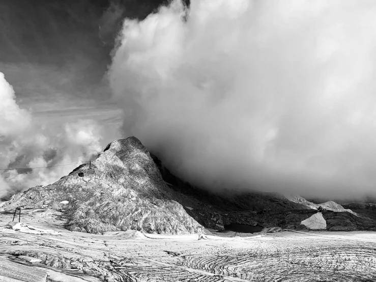 there is a very tall mountain with some clouds rolling in