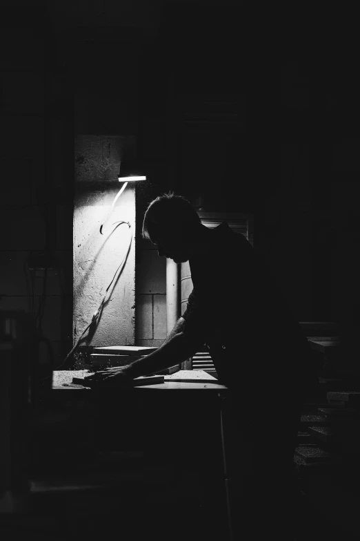 a black and white photo of a person in a dark room, working hard, profile picture, tending on arstation, dark warm light