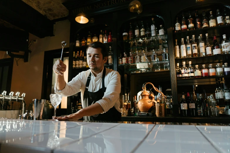 a bartender working behind the bar is pouring himself a drink