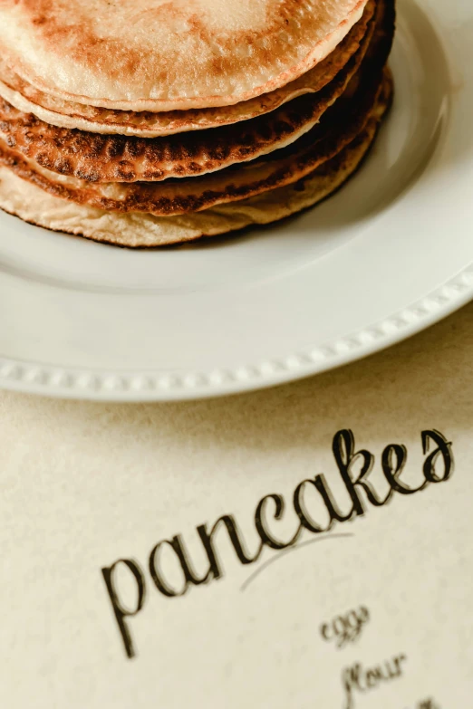 pancakes are stacked on a plate next to a menu