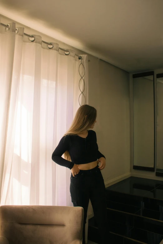 a woman standing in front of a bed looking at the curtains