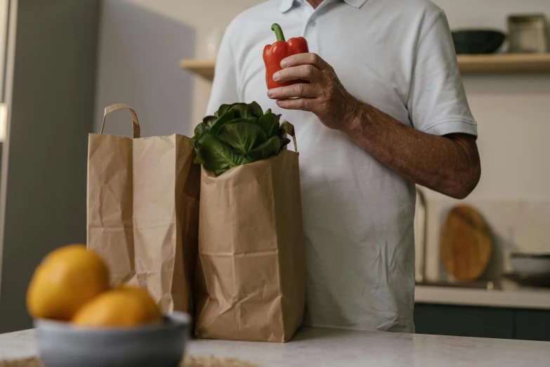 a man holding a pepper in a paper bag, pexels contest winner, middle - age, getting groceries, avatar image, close - up photograph