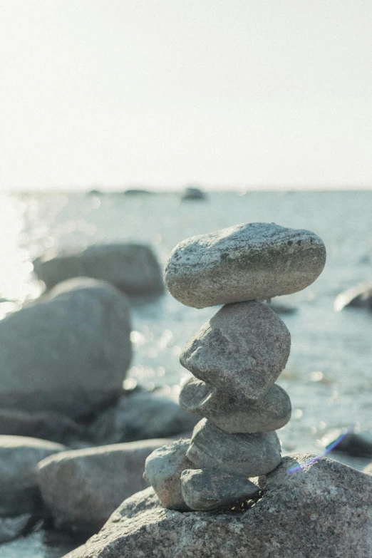 a stack of rocks sitting on top of a beach, lynn skordal, grey