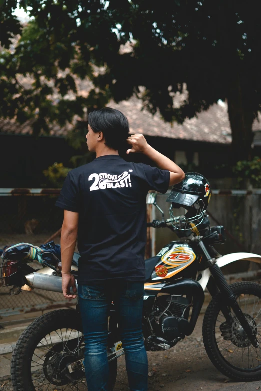 a man standing next to his motorcycle in a village