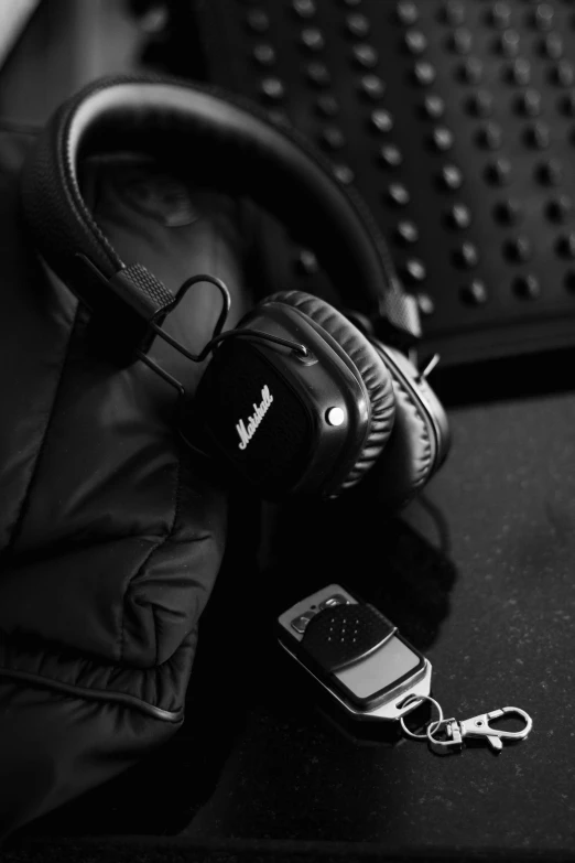 a pair of headphones sitting on top of a table, a black and white photo, by Adam Marczyński, wearing a leather jacket, dark wallpaper, uploaded, exquisite black accessories