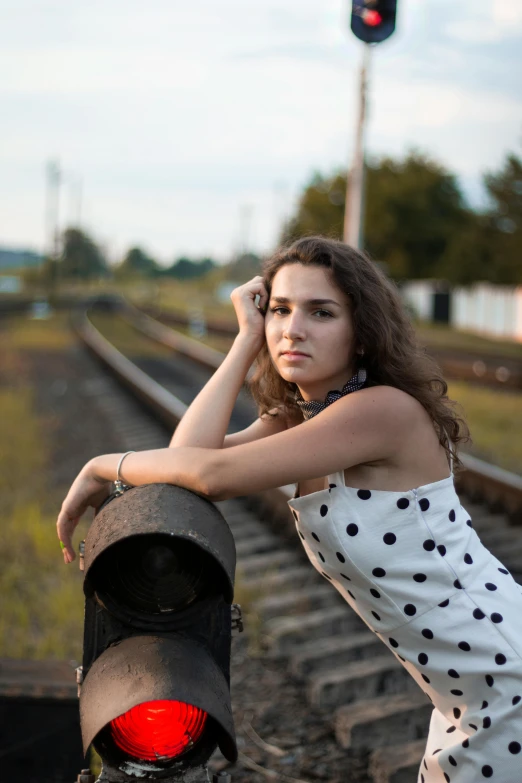 a woman standing next to railroad tracks with her hand on her head