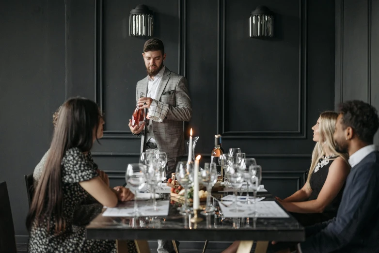 a waiter in grey standing before his diners