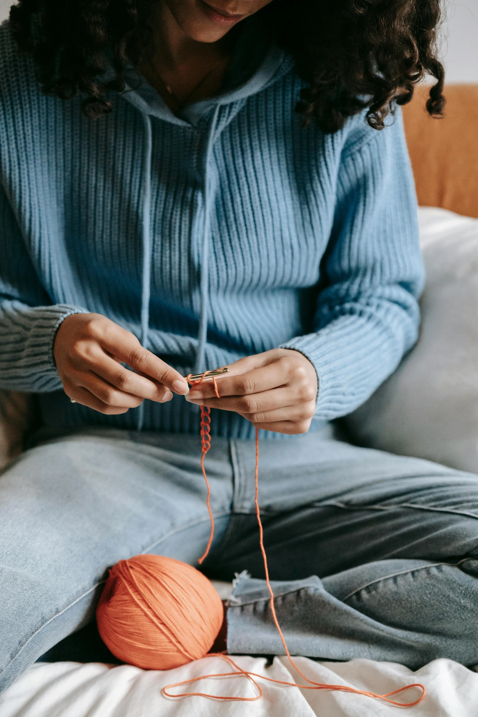 the woman is knitting the orange yarn into a ball