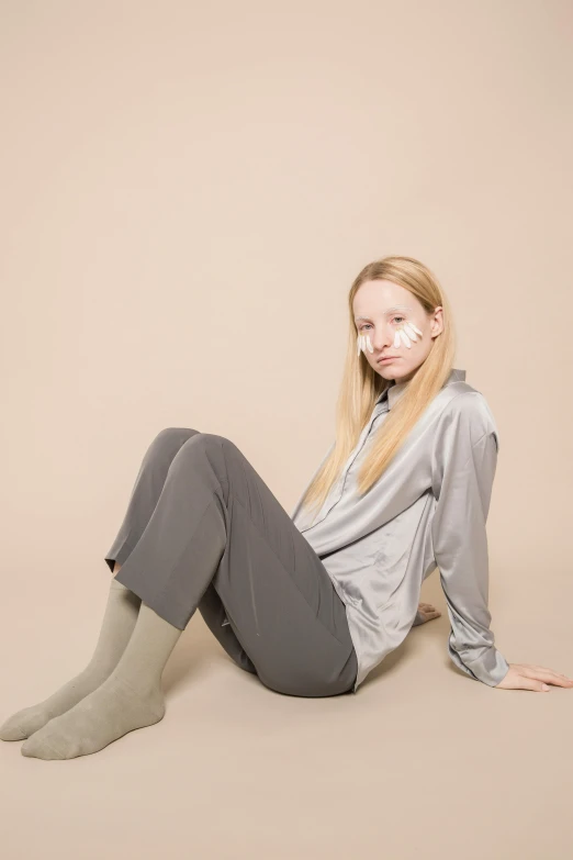 a woman sitting on the ground with her legs crossed, with grey skin, julia hetta, wearing pajamas, product introduction photo