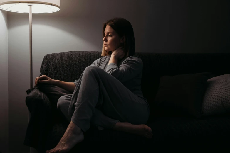 a woman sitting on a couch in the dark looking at her laptop