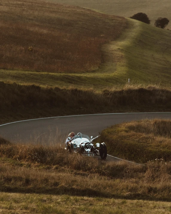 a motorcycle that is sitting on the side of a road, by Daniel Seghers, pexels contest winner, convertible, on a hill, rally driving photo, thumbnail