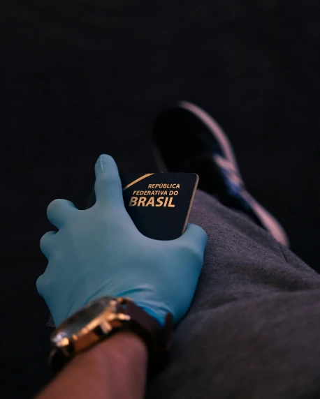 a person wearing a blue glove holding a passport