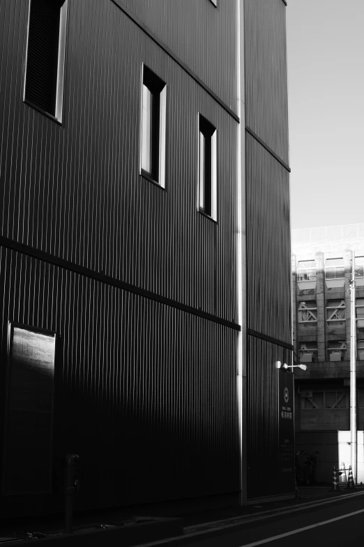 a black and white photo of a building, inspired by Pierre Soulages, unsplash, manchester, warehouses, metal cladding wall, black house