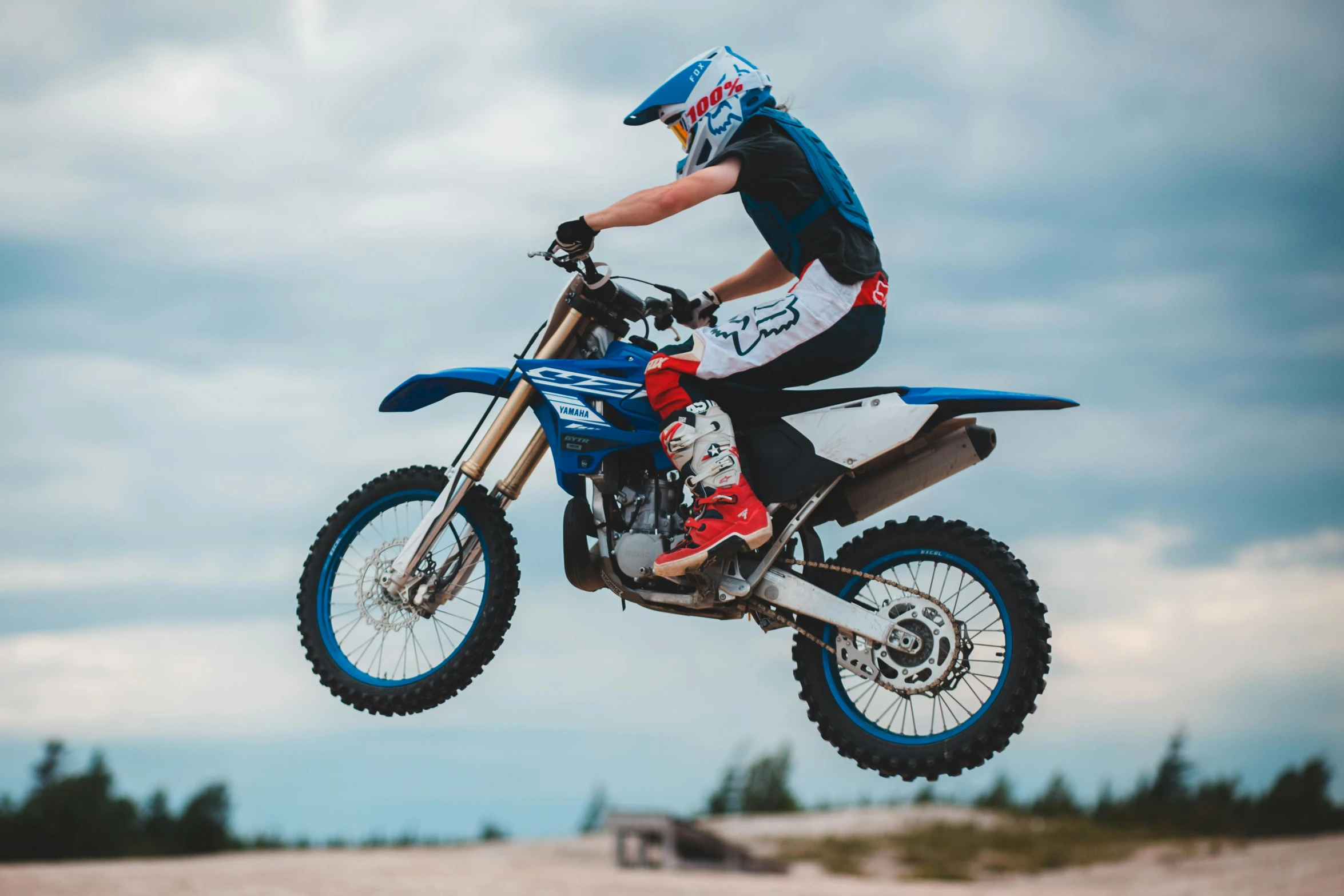 a man flying through the air while riding a dirt bike, pexels contest winner, sassy pose, blue, avatar image, woman