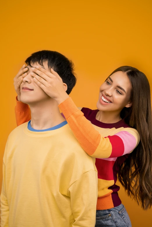 a man covering his eyes next to a woman, trending on pexels, aestheticism, yellow and ornage color scheme, teen boy, playful smile, half asian