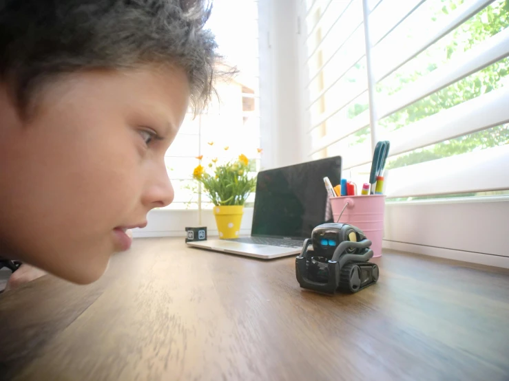 a young boy looking at a toy car on a desk, a picture, pexels contest winner, les automatistes, biomechanoid, programmable black goo, with backdrop of natural light, sitting in front of computer