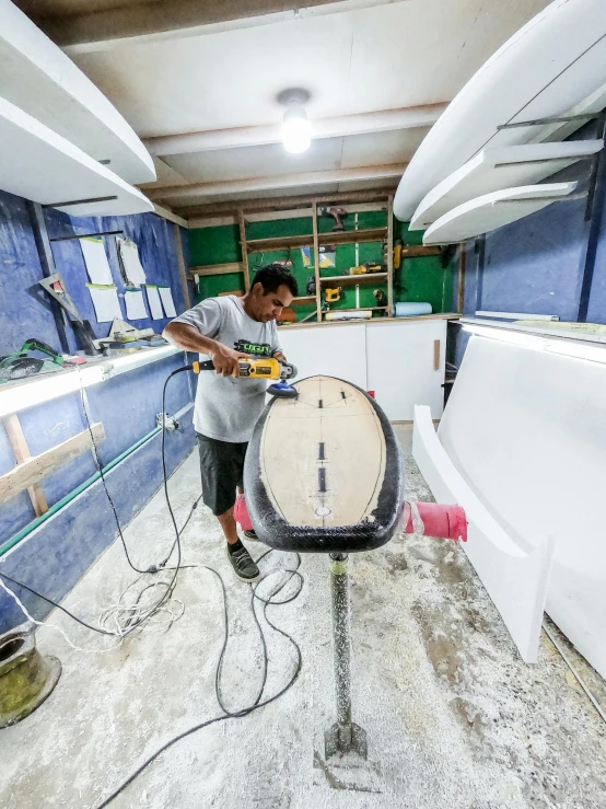 a man that is standing in a room with a surfboard, in a workshop, profile image, maintenance photo, samoan features