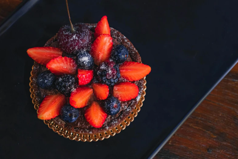 a chocolate cake topped with strawberries and blueberries, inspired by Richmond Barthé, pexels contest winner, art nouveau, background image, fresh fruit, stroopwaffel, dark-skinned