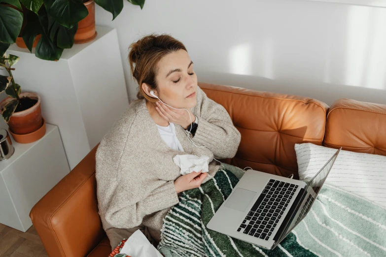 a woman sitting on a couch using a laptop, by Julia Pishtar, trending on pexels, happening, sick with a cold, with headphones, avatar image, worksafe. instagram photo