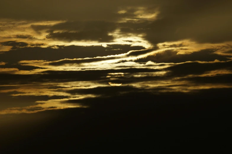 a dark picture of the sun behind clouds